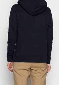 Felpa blu navy realizzata in morbido misto cotone, presenta una tasca frontale a marsupio, polsini a costine e un cappuccio ampio foderato.