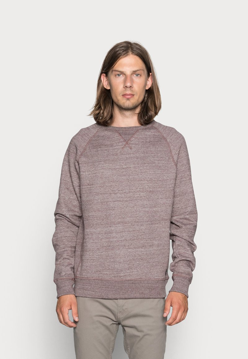 Sudadera de cuello redondo en color burdeos, fabricada con un suave tejido de punto, que presenta mangas raglán, puños acanalados y un acabado texturizado.