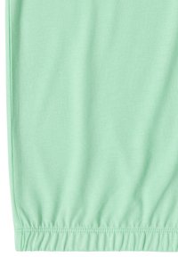 Tissu vert menthe avec ourlet élastiqué et détail de couture piquée, probablement une partie de la section inférieure d'un vêtement.