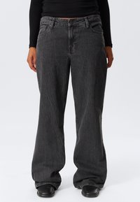 Jeans de denim largi, de culoare gri închis, cu un finisaj texturat, cinci buzunare, închidere cu nasture și bucle pentru curea. Detalii cusute de-a lungul cusăturilor.