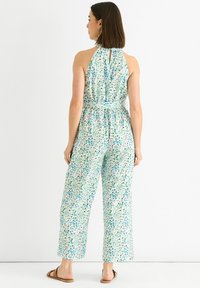 Halter neck jumpsuit in a lightweight, multicolor fabric featuring a pattern of green and blue speckles; relaxed-fit, wide legs, and a keyhole back.