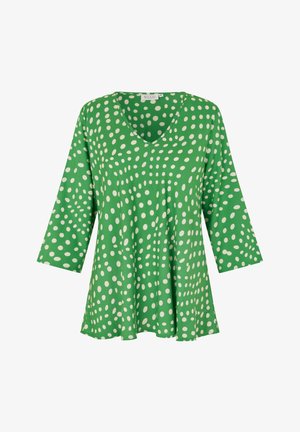 Haut vert à encolure en V avec manches trois-quarts, présentant un motif de grands pois blancs et une coupe fluide et ample. Texture de tissu douce.