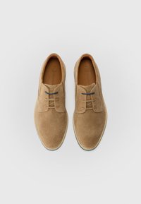 Braune Wildleder-Schnürschuhe mit runder Zehenform, gesteppten Akzenten und einer hellbraunen Gummisohle. Das Innere ist mit hellbraunem Leder ausgekleidet.