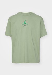 T-shirt vert clair à manches courtes avec logo Jumpman vert et texte noir « Flight » centré sur la poitrine.