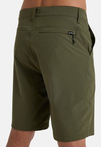 Shorts verde oliva realizzati in un tessuto leggero, caratterizzati da una tasca posteriore con un piccolo cartellino logo e un dettaglio con cordoncino in vita.