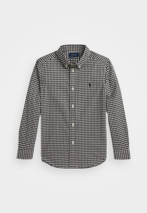 Juostuota ilgomis rankovėmis palaidinė juodos ir baltos spalvos. Mygtukų apykaklė, priekis su mygtukų uždarymu, klasikinis kirpimas ir siuvinėtas logotipas ant krūtinės.