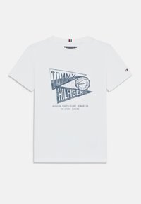 Weißes Baumwoll-T-Shirt mit blauem grafischen Druck, der den Schriftzug "TOMMY HILFIGER" und Städtenamen zeigt, kurzer Ärmel und kleines Logo-Detail am Ärmel.