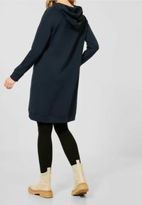 Marinblå huvtröja med lång ärm, avslappnad passform och sidofickor. Matchas med svarta leggings och beige ankelstövlar.