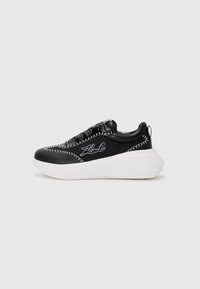 Baskets noires avec semelles blanches, dotées d'un dessus texturé, de coutures contrastées et d'une boucle au talon pour un enfilage facile. Logo de la marque inclus.