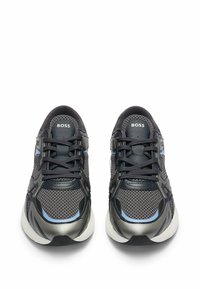 Chaussures de sport noires et grises avec une tige en mesh, des accents en cuir et des détails texturés. Présente un logo et des lacets plats. Semelle blanche rembourrée.