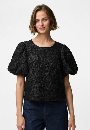 Haut noir texturé avec des manches courtes bouffantes et un col rond. Le tissu présente un design froissé, associé à un bas en denim foncé.