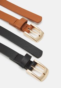 Dvoje kožených opasků: jeden v tan barvě se zlatou sponou a jeden černý se zlatou sponou. Oba mají hladkou strukturu a úzký design.