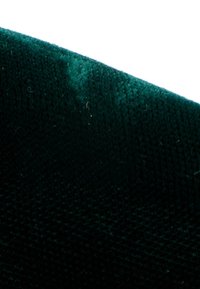 Gros plan d'un tissu texturé vert foncé avec un bord plié et un motif tissé visible.