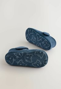 Dunkelblaue Hausschuhe mit einer strukturierten Oberseite, ausgestattet mit einem Klettverschluss und einer gemusterten Sohle, die Katzenköpfe in hellblau darstellt.
