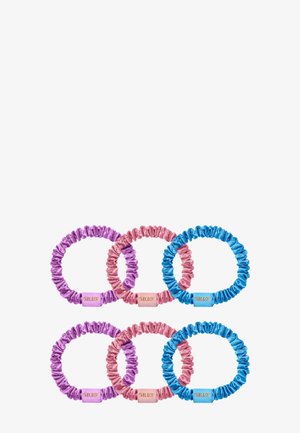 Six chouchous en soie rassemblés en violet, rose et bleu, chacun avec une petite étiquette rectangulaire portant la mention "SILKE" sur fond blanc.