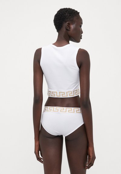 Bílý zkrácený top a odpovídající bikiny s elastickým pasem zdobeným zlatým řeckým klíčem. Hladký, pružný bavlněný materiál.