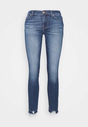 Jeans skinny in denim blu scuro, caratterizzati da una lavatura sbiadita, design con cinque tasche, chiusura frontale con bottoni e orli sfrangiati.