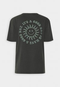 Camiseta de algodón verde oscuro con un cuello redondo. La parte posterior presenta un diseño de sol con una cara sonriente y el texto: "ES UN BUEN DÍA PARA TENER UN BUEN DÍA."