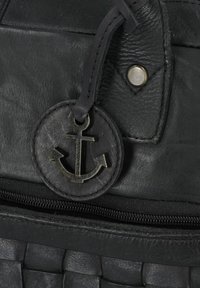 Zwarte leren handtas met een geweven textuur, een ronde ankerembleem en een ritssluiting. Metalen accenten maken het ontwerp compleet.