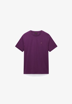Ljubičasta pamučna majica s okruglim izrezom, kratkim rukavima i malim vezanim grbom blizu prsa. Glatka tekstura, regularni kroj.