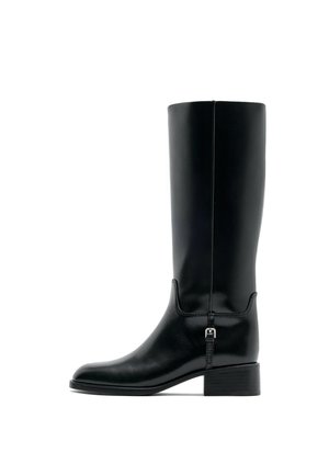 Botte noire en cuir montante jusqu'au genou avec un petit talon et un petit détail de boucle sur le côté, présentée de profil sur fond blanc.