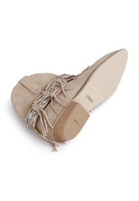 Beige suede ankle boot with fringe detail, silver hardware, flat heel, and textured rubber sole. Smooth interior lining. Flat profile.