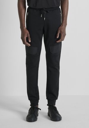 SLIM FIT IN INTERLOCK WITH FLAPS ON LEGS AND BACK PRINT - Pantalon de survêtement - black