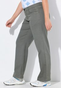 Pantalons gris à jambe droite avec une texture lisse, poches avant et fermeture à bouton. Assortis à des baskets blanches avec des accents bleus.