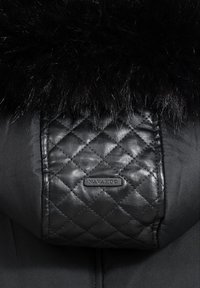 Black puffer jacket with glossy black faux fur collar and a quilted leather patch featuring a sewn-on brand label.