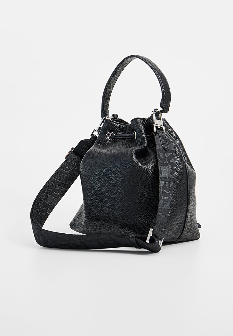 Schwarze Lederzugtasche mit strukturierten Oberflächen, kurzem Griff und breitem abnehmbaren Schultergurt mit dezentem Muster.