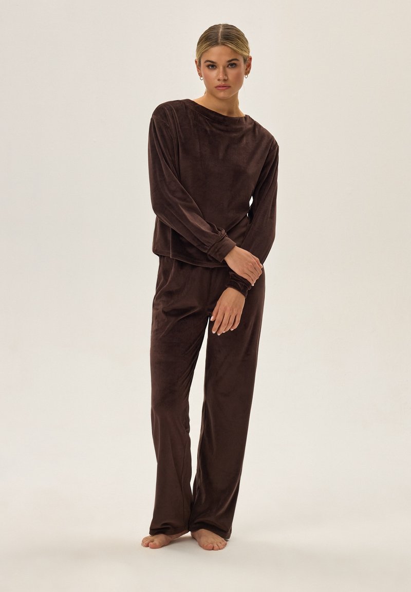 Brązowy, miękki zestaw odzieży dresowej z weluru, składający się z długiego rękawa z okrągłym dekoltem i luźnym kroju, zestawiony z luźnymi spodniami.