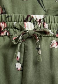 Tissu vert à imprimé floral, taille élastique nouée d'un nœud en tissu à imprimé floral assorti.