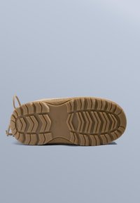 Gummisula med ett texturerat, zickzackmönster; ljusbrun färg med en överdel av vävt tyg. Har en dragflik för enkel användning.