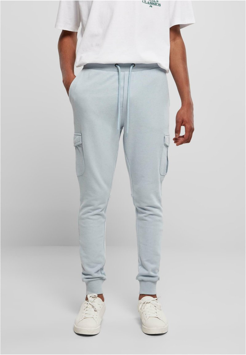 Lys blå bukser med lommer på siden, elastisk midjebånd og mansjetter, laget av mykt stoff. Bært med hvite joggesko og en uformell t-skjorte.