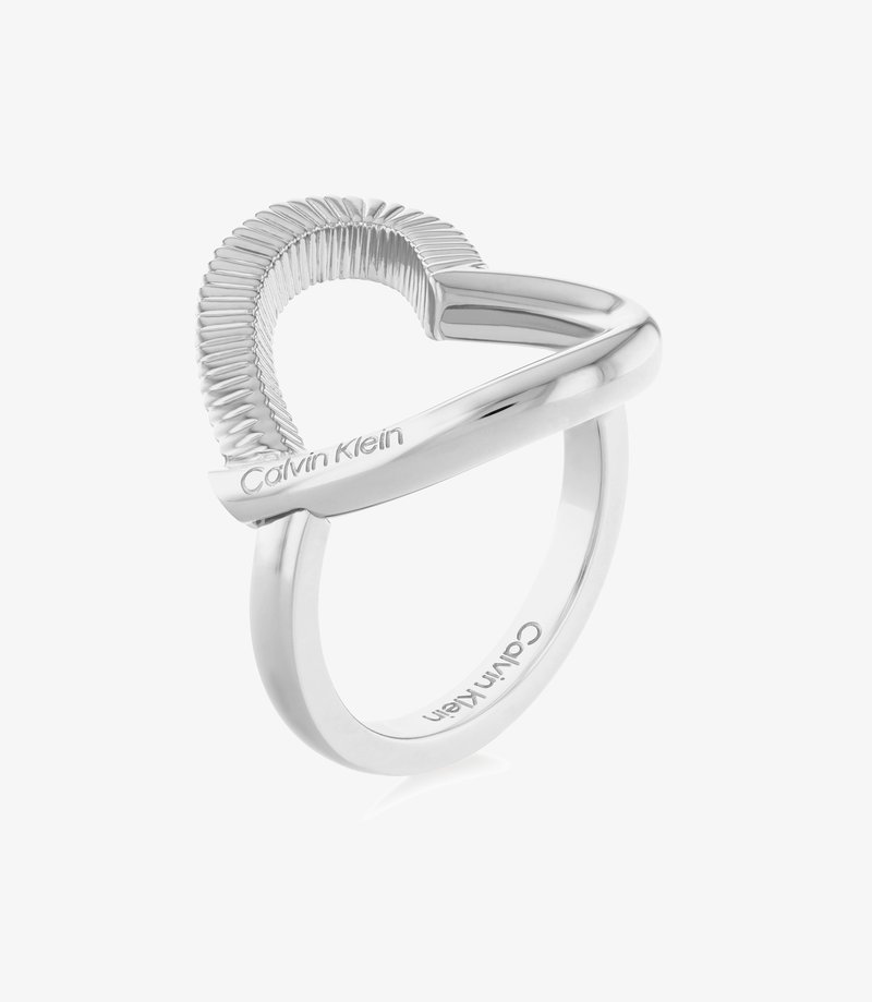 Sølvring med en bølget, tekstureret band og glatte, polerede accenter, indgraveret med "Calvin Klein." Moderne, minimalistisk design.