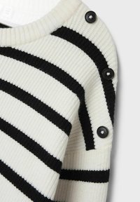 Gestreifter Pullover in Cream und Schwarz, mit gerippter Textur, Rundhals Ausschnitt und drei schwarzen Knöpfen an der Schulter.