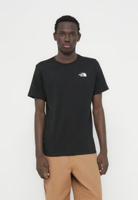 Μαύρο βαμβακερό T-shirt με κοντά μανίκια, στρογγυλή λαιμόκοψη και μικρό λευκό λογότυπο στο στήθος. Ομαλή υφή και κανονική εφαρμογή.