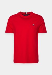 T-shirt rossa in cotone con scollo rotondo, maniche corte e un piccolo logo ricamato in blu navy sul petto. Tessuto liscio e vestibilità classica.