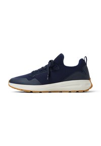 Zapatilla deportiva azul marino con parte superior de malla, suela de goma y punta redonda. Presenta un diseño de cordones y una suela exterior en tono marrón contraste.