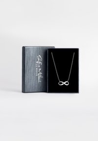 Silver infinityhalsband på ett tunt kedja, presenterat i en elegant svart och silverlåda med en strukturerad yta.