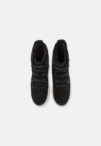 Zapatillas altas de ante negro con forro de piel, cordones planos negros y suela de goma blanca. Presenta ojales de metal para los cordones.