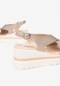 Sandali platform beige con tomaia in pelle liscia, punta aperta, cinturino alla caviglia e dettaglio in fibbia argento. Suole in gomma bianca spessa per un'altezza extra.