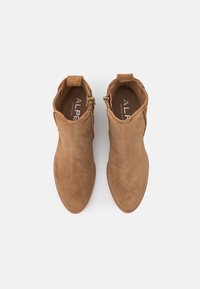 Braune Wildleder-Ankelboots mit glatter Textur, spitzem Zeh, seitlichem Reißverschluss und Zuglasche auf der Rückseite. Robuste Sohle mit minimaler Nahtdetail.
