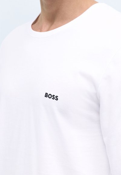 T-shirt blanc à manches longues en coton, avec un logo "BOSS" brodé en noir sur le côté gauche de la poitrine. Texture lisse, col rond.
