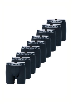 Neun schwarze Boxershorts mit weißen Bund, jeweils mit "SCHIESSER," gebrandmarkt, in einer versetzten Linie auf weißem Hintergrund angeordnet.