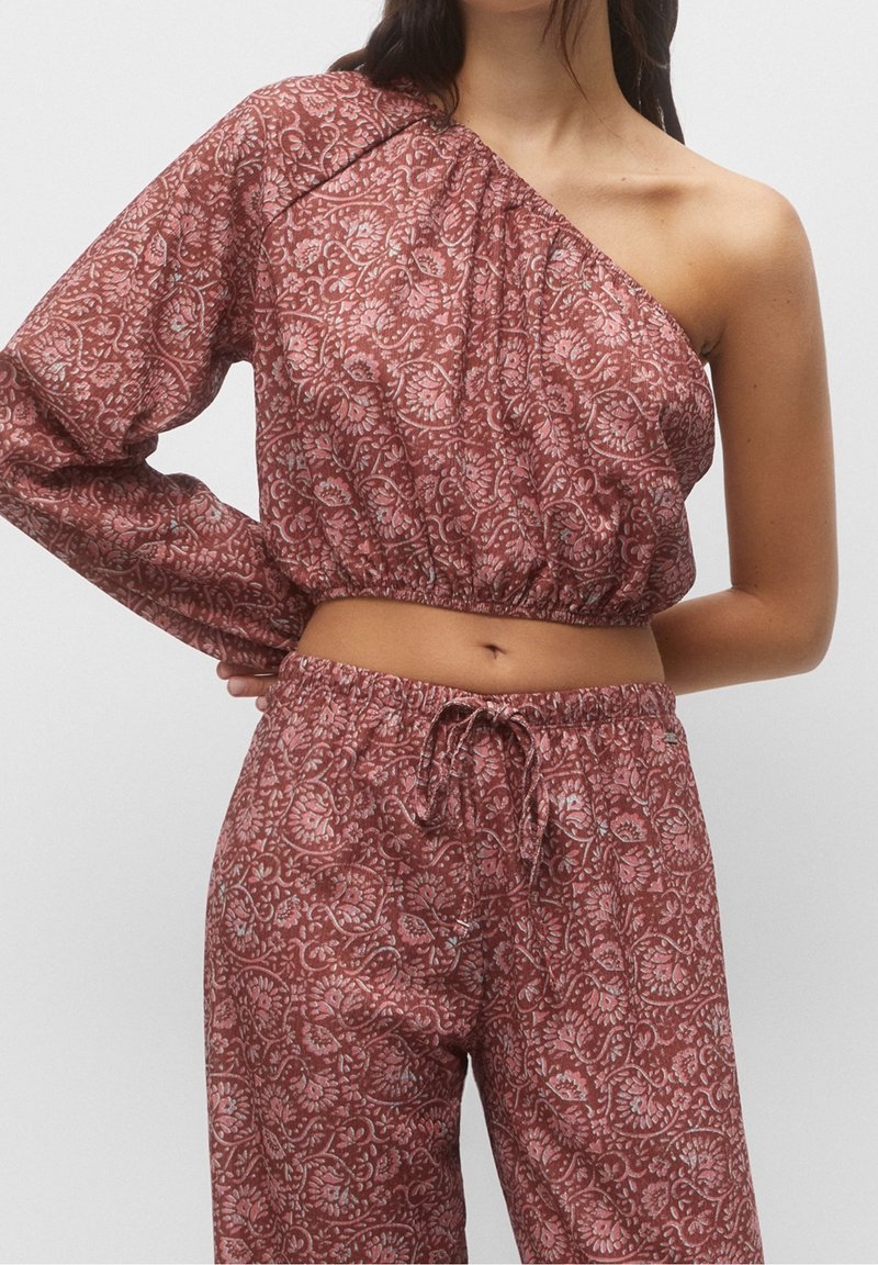 Ensemble de vêtements d'intérieur bordeaux à motifs comprenant un haut asymétrique à une épaule et un pantalon à taille élastique avec cordon de serrage. Tissu lisse et léger.