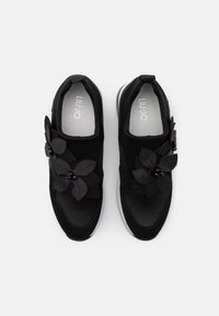 Schwarze Sneaker mit einem weichen Textilobermaterial, synthetischen Blumenakzenten, einer gepolsterten Sohle und einem glatten Innenfutter mit Markenlogo.