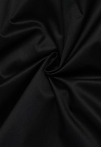 Tessuto nero, texture liscia con una leggera lucentezza, caratterizzato da motivi a righe diagonali. Piegato per mostrare la caduta e la qualità del materiale.