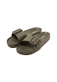 Sandalias de goma verdes con una correa ancha que presenta una hebilla rectangular. Plantilla texturizada y suela lisa para mayor comodidad.