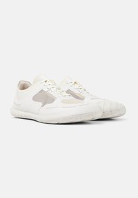 White athletic shoes with a smooth leather upper, mesh accents, and a textured rubber sole. Features round toe and lacing system.